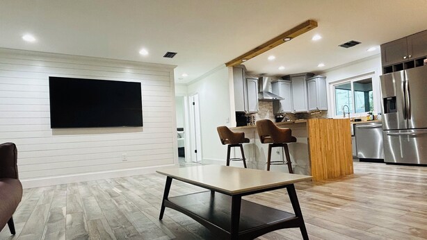 Una cocina moderna con una isla de madera, electrodomésticos de acero inoxidable y un comedor con mesa y sillas.