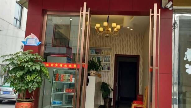 A hotel entrance with a red facade, a glass door, a chandelier, and a signboard. - Mingxin Hotel (Enshi City)