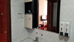 A bathroom with a mirror, a sink, a towel rack, and a soap dispenser. - Mingxin Hotel (Enshi City)
