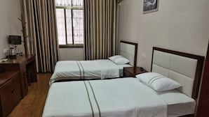 A hotel room with two single beds, a desk with a lamp, a window with curtains, and a wall-mounted picture. - Mingxin Hotel (Enshi City)