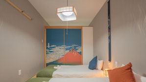 Camera d'albergo con due letti, un grande murale, una lampada a sospensione e un comodino con lampada.