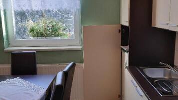 A compact kitchen with a window, a sink, and a table with a chair.