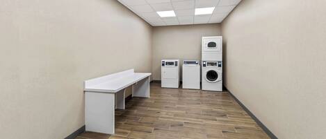 A laundry room with a bench, two washing machines, and a dryer.