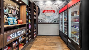 A hotel lobby with a 'Welcome' sign, a 'Treats' sign, and shelves stocked with snacks and beverages. - Hampton Inn & Suites Sherman (Sherman)