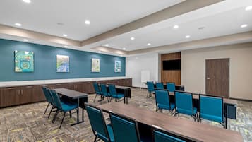A conference room with a long table and chairs, teal walls, and artwork.