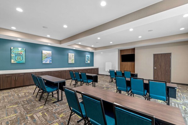 Un salón de conferencias con una mesa larga y sillas, paredes color turquesa y obras de arte.