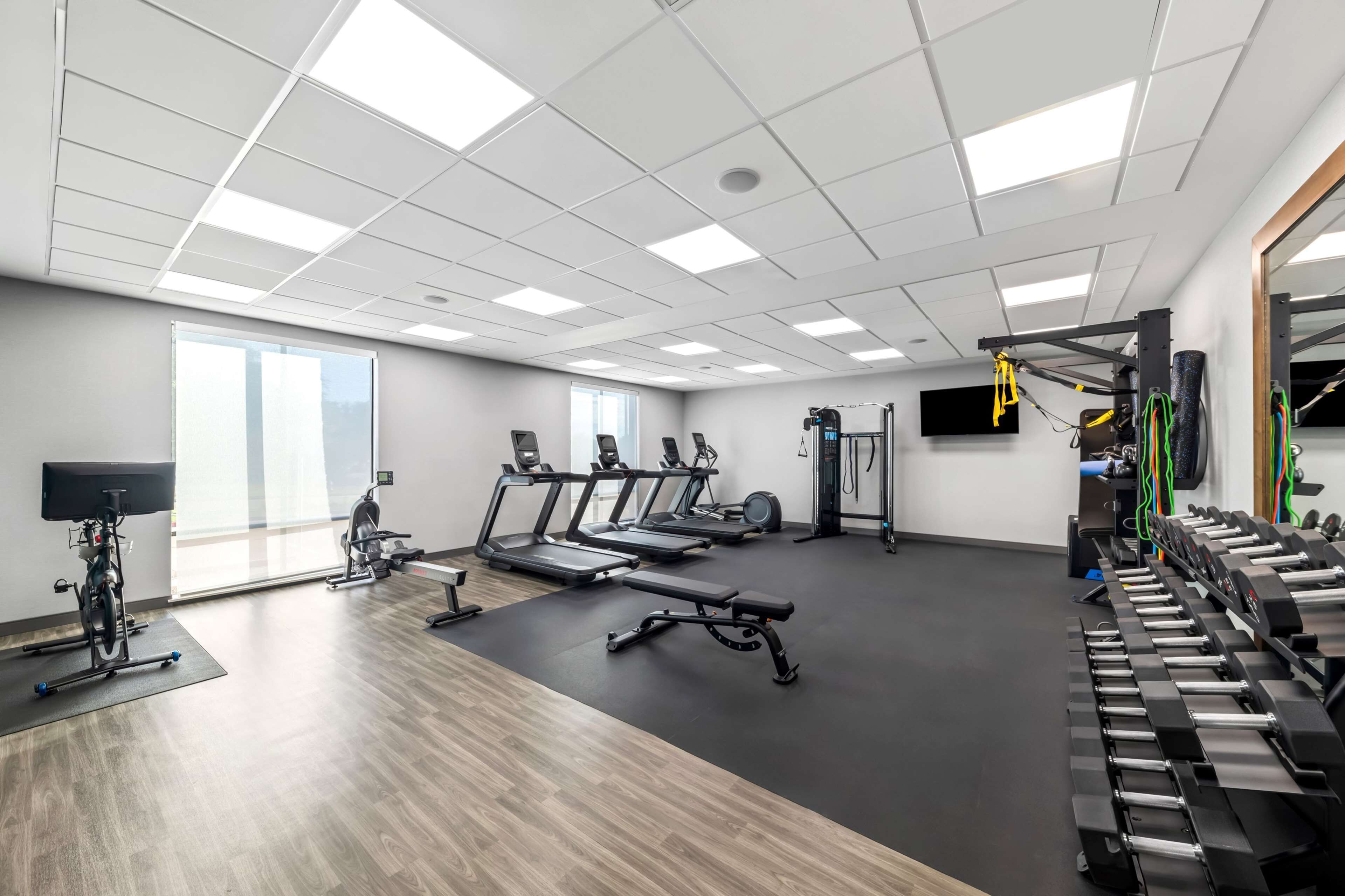 A gym with treadmills, stationary bikes, a bench, and weight machines.