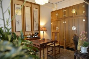 A room with a wooden cabinet, a table with chairs, a lamp, and framed artwork on the wall. - Ancient City Old Courtyard Boutique Hotel (Beijing)
