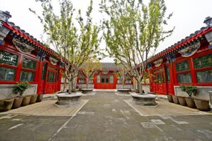 A courtyard with traditional architecture, featuring red buildings and stone lanterns. - Ancient City Old Courtyard Boutique Hotel (Beijing)
