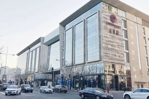A modern building with a large glass facade, a prominent logo, and a parking lot with several cars. - Ancient City Old Courtyard Boutique Hotel (Beijing)