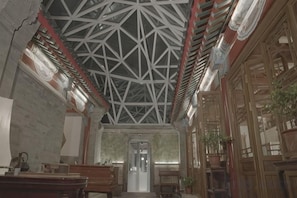 A room with a high ceiling, wooden beams, and a door at the far end. - Ancient City Old Courtyard Boutique Hotel (Beijing)