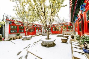 A courtyard with traditional architecture, potted plants, and a snow-covered ground. - Ancient City Old Courtyard Boutique Hotel (Beijing)