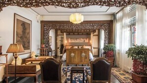 Un interior tradicional con un armario de madera, dos sillas, una mesa y una lámpara colgante.