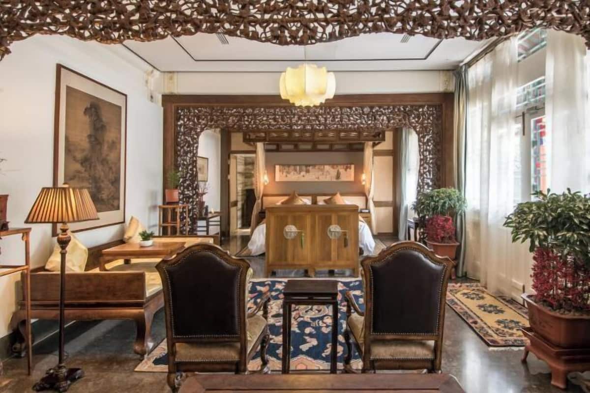 A traditional interior with a wooden cabinet, two chairs, a table, and a hanging light fixture.