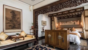 Una habitación tradicional con sofá, un armario, una cama y un cuadro grande en la pared.