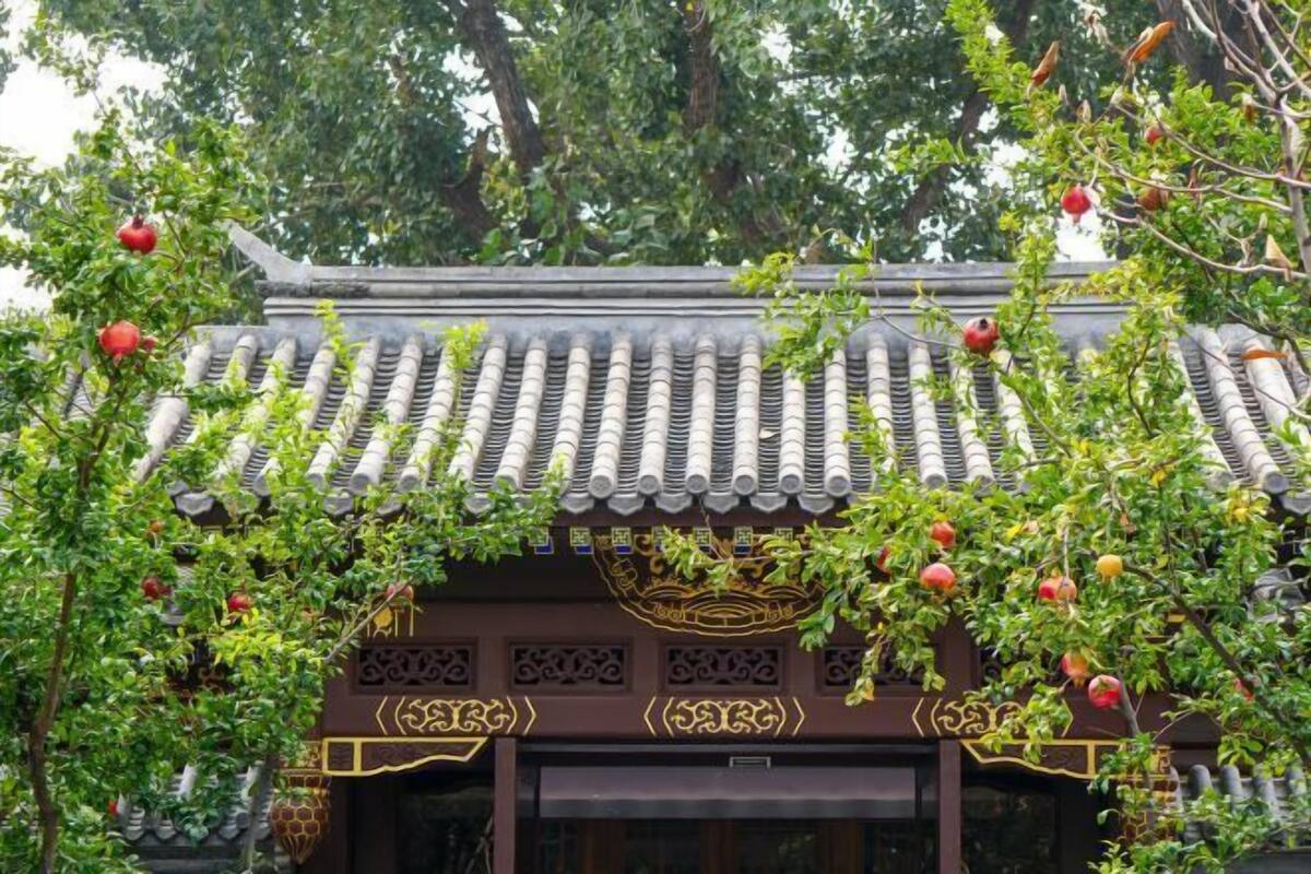 A traditional building with a tiled roof, decorative patterns, and hanging pomegranates.