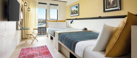 Habitación de hotel con una cama grande, un televisor montado en la pared, un tapete rojo y una ventana con vistas a edificios.