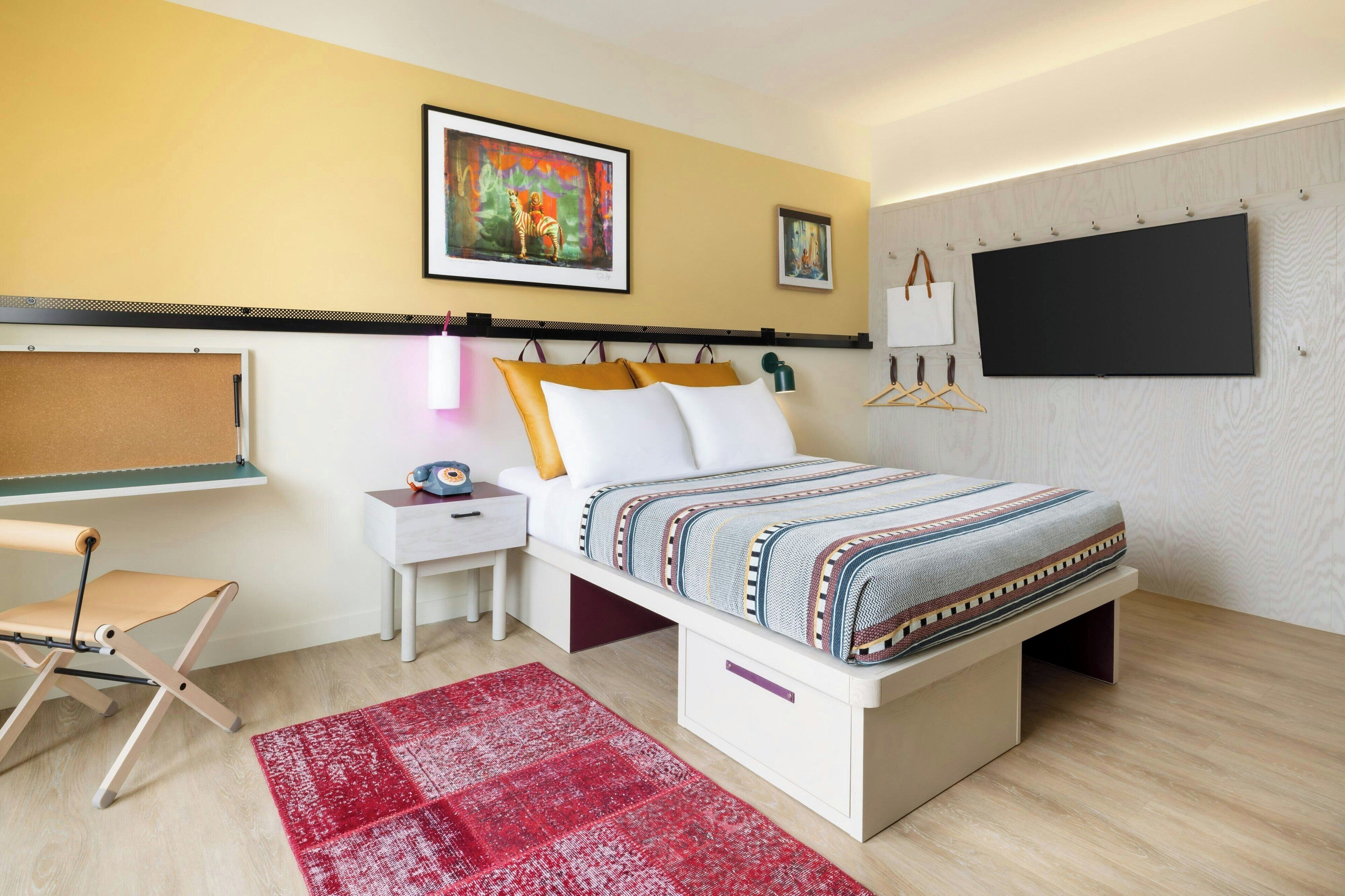 Une chambre à coucher moderne avec un lit, des tables de chevet, un bureau et un tapis rouge.