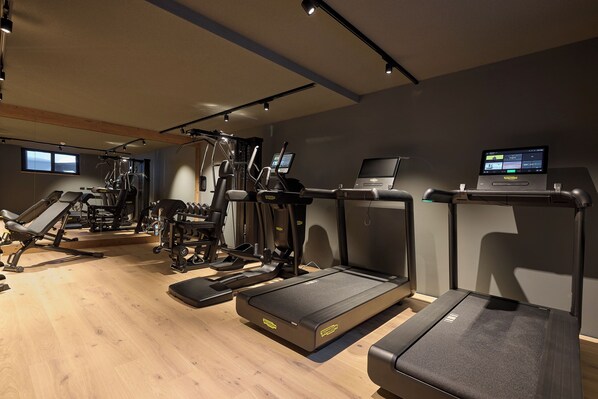 Un gimnasio moderno con cintas de correr, máquinas elípticas y equipo de levantamiento de pesas.