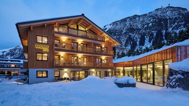 Ein mehrstöckiges Hotel mit Holzhülle und Balkonen in einer verschneiten Berglandschaft.