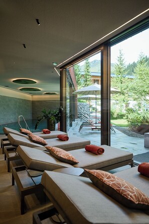 Zona de spa con sillones reclinables, pared de vidrio y vistas al exterior.