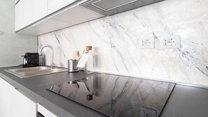 A modern kitchen with a marble backsplash, stainless steel sink, and a coffee maker. - Italianway Comfort - Fara 29 (Milan)
