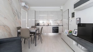 A modern kitchen with a built-in oven and a dining area with a table and chairs. - Italianway Comfort - Fara 29 (Milan)