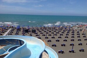 A beach with a water slide, umbrellas, and beach chairs. - Holiday Properties Le Vele (Montalto Marina)