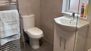 A bathroom with a toilet, a sink, and a towel rack. - Chaucer House Retreat - Leicester (Leicester)
