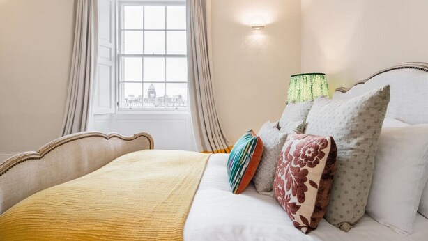 A hotel room with a bed, curtains, a lamp, and a window with a view.
