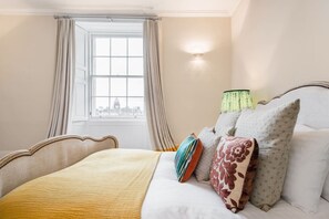 A hotel room with a bed, curtains, a lamp, and a window with a view. - Flat With Castle Views in a New Town Georgian Townhouse (Edinburgh)