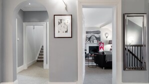 A hallway with a staircase, a framed picture, a fireplace, and a mirror.
