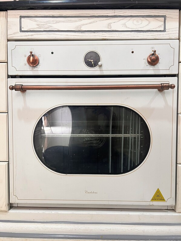 Un horno antiguo Carlens con puerta de cristal frontal, mandos y un letrero de precaución.