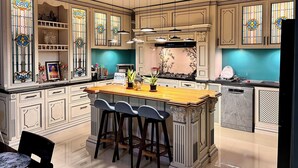 A spacious kitchen with a central island, bar stools, and decorative stained glass windows.