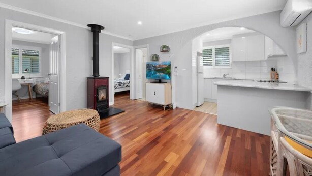 A modern living room with a fireplace, a television, and a kitchen area with white cabinets and a countertop. - 2BDR Holiday Flat near Bright-Entire Place (Freeburgh)