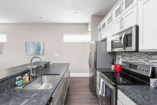A modern kitchen with a stainless steel sink, a microwave, and a stove.