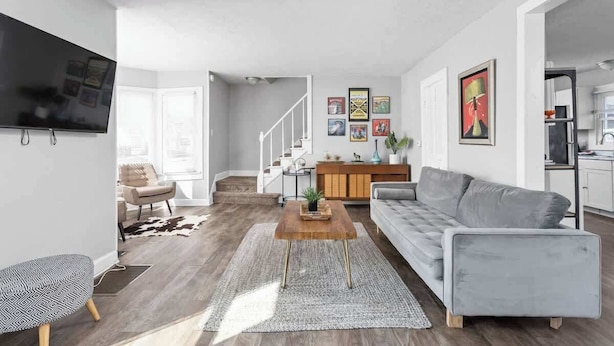 Ein modernes Wohnzimmer mit einem grauen Sofa, einem Holztisch und einem flachbildfernseher an der Wand.