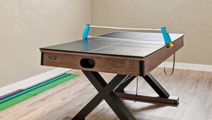 Uma mesa de pingue-pongue com uma rede, um logotipo na lateral e uma janela ao fundo.