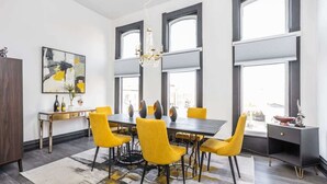 Un espace repas moderne avec une grande table rectangulaire, des chaises jaunes et un lustre.