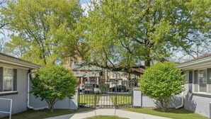 Un quartier résidentiel comprenant deux maisons, une allée pavée et une entrée fermée par un portail.