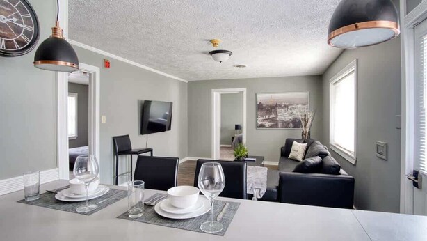 Un espace repas moderne avec une longue table, des chaises noires et une grande horloge murale.