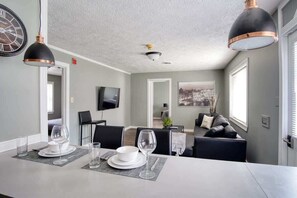 Een moderne eetruimte met een lange tafel, zwarte stoelen en een grote klok aan de muur.