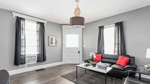A modern living room with a black leather sofa, a white coffee table, and a grey rug. - New Castle Retreat | Beautiful Duplex • Near Parks (New Castle)