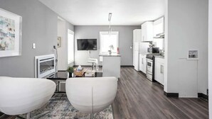 A modern kitchen with white cabinets, a microwave, and a stove. There is a dining area with two white chairs and a small table. - New Castle Getaway | Fireplace • Prime Location (New Castle)
