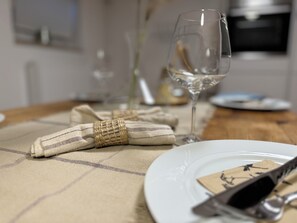 A dining table with a white plate, a wine glass, and a napkin with a woven pattern. - Exklusive Business und Ferienwohnung (Cadolzburg)