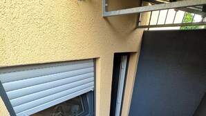 A narrow stairway leading to a balcony with a window, a small seating area, and a door.