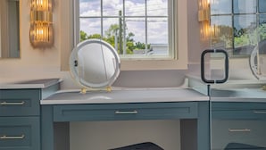 A bathroom with a large window, a round mirror, and a stool.