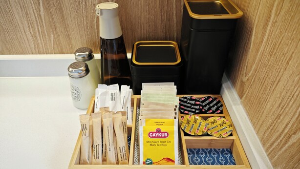 A wooden tray with tea bags, a bottle, and containers on a kitchen counter. - Marmada Suites (Istanbul)