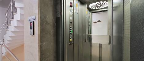 An elevator with a control panel, a digital display, and a decorative ceiling light fixture.