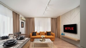 A modern living room with a sofa, a coffee table, and a TV displaying "NETFLIX". - Marmada Suites (Istanbul)